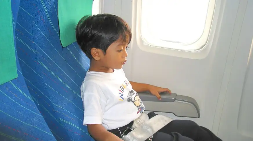 un enfant assis et attaché dans un avion